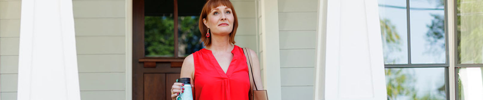 Megan, an adult female patient with rheumatoid arthritis, stands outside her house holding a thermos and tote bag. She has a determined look on her face as she looks up at the sky