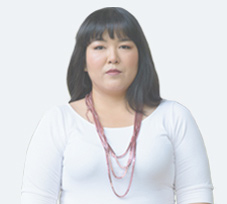 Young female RA patient named Christine wearing a necklace looks into the camera with a calm expression