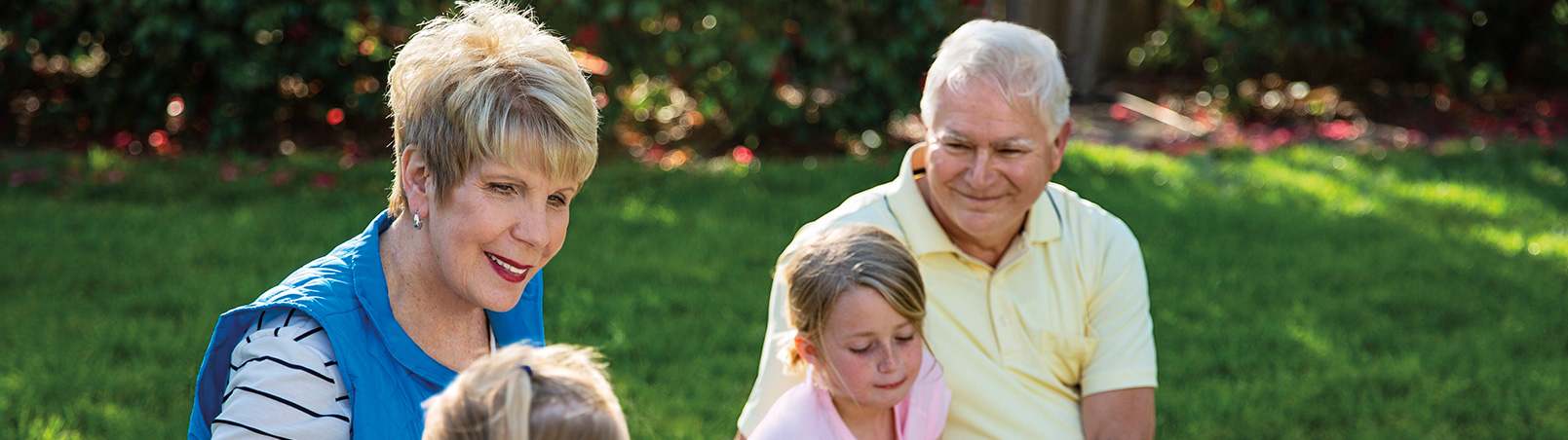 A grandmother (the patient named Peggy) and grandfather play with their grandkids outside on the grass